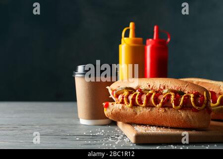 Tasty hot dogs, coffee and sauces on wooden background Stock Photo