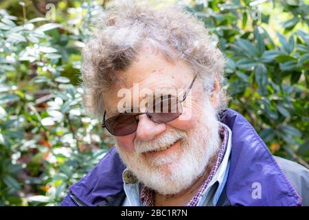 Friendly happy bearded senior male with a twinkle in his eye, a warm, kind healthy confident elderly man outside Stock Photo