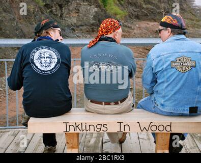 Harley Day Out.Three Harley Davidson Riders sitting on a wooden bench waiting to see the tidal surge near The Bay of Fundy Nova Scotia Canada. Stock Photo