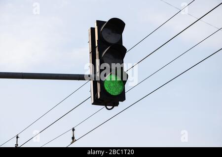 Green traffic light with green direction light against soft blue sky background Stock Photo