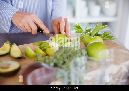Woman cutting healthy green apples and produce on cutting board Stock Photo