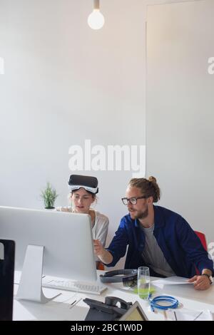 Computer programmers programming virtual reality simulator glasses at computer in office Stock Photo