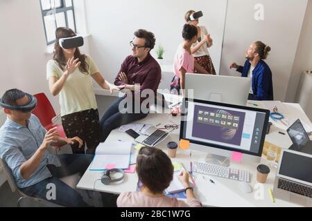 Computer programmers testing virtual reality simulator glasses in open plan office Stock Photo