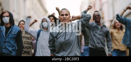 Group of activists giving slogans in a rally. Men and women marching together in a protest in the city. Stock Photo