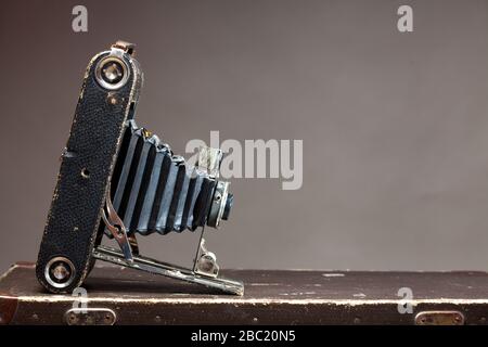 Old vintage camera lying on suitcase on gray background Stock Photo