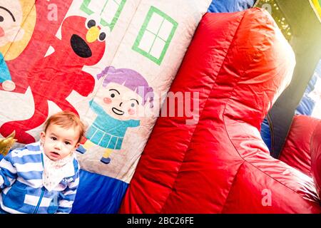 Girl with coat next to an inflatable castle, alone and sad. Stock Photo