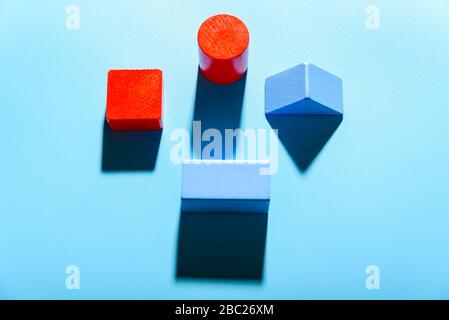 Three geometric figures of solid colors illuminated with hard light on simple blue background. Stock Photo