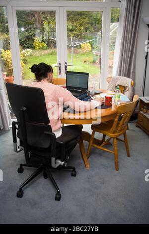 Female office worker sitting at table working from home Stock Photo
