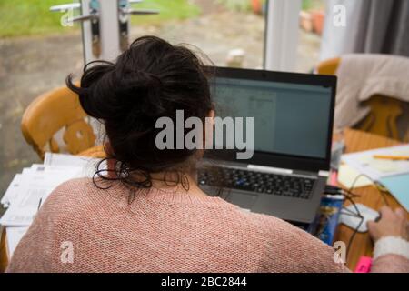 Female office worker sitting at table working from home Stock Photo