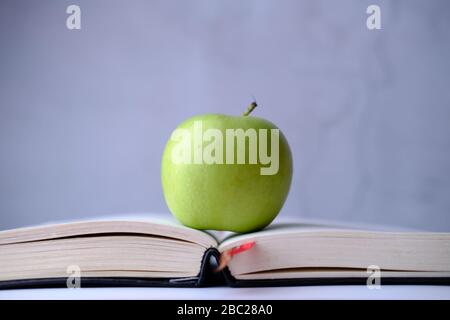 Close up of green apple on book isolated on white . Stock Photo