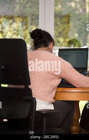 Female office worker sitting at table working from home Stock Photo
