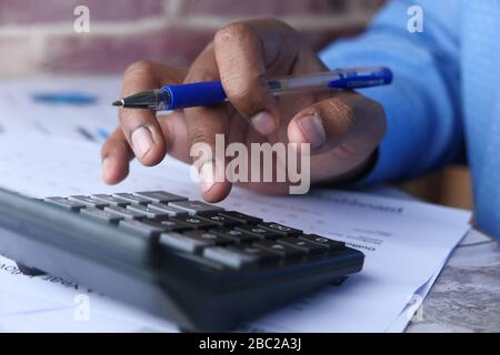 Close up of young man using calculator  Stock Photo