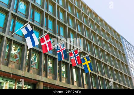 Major Scandinavian countries flags on a facade of a modern hotel building. From left to right: Finland, Denmark, Iceland, Norway, Sweden Stock Photo