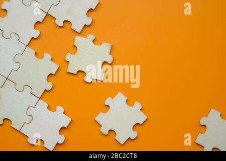 Pieces of puzzle on orange background, close up. Stock Photo
