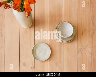 Handmade plates Top view photo with copy space Fresh flower bouquet in craft ceramic vase and handmade plates on wooden table Stock Photo