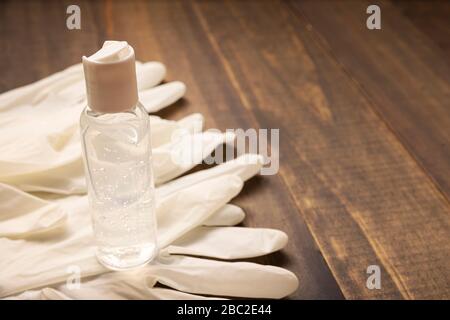 medical latex gloves and hand sanitizer gel bottle for protection on wooden background. Useful for pandemic prevention concept Stock Photo