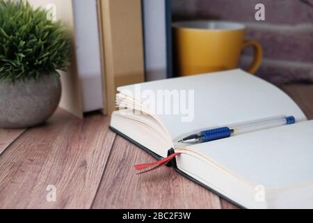 Close up of open diary, pen and books on table. Stock Photo