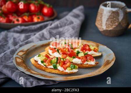 Three crostini, traditional Italian sandwich with tomatoes and cucumbers. Breakfast on plate Stock Photo