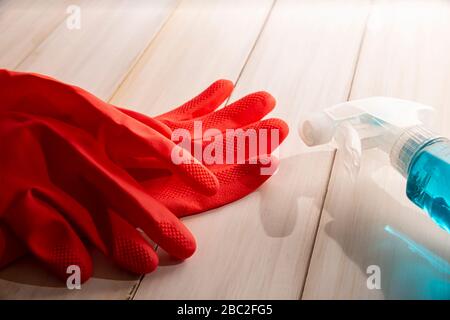 red rubber gloves and liquid detergent in sparay bottle on wooden background, cleaning and sanitization concept Stock Photo