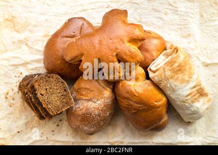 An assortment of bakery products produced by a small bakery. Bread bakery products on pita bread, view from the top. Stock Photo