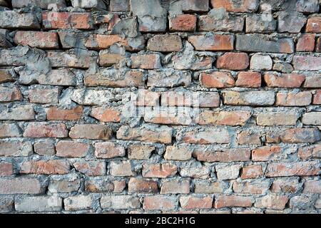 Horizontal photo of an old red wall. The surface of the wall is dirty and has a decorative relief. Stock Photo