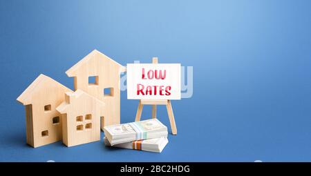 Figurines of houses and an easel with low rates. Low demand for real estate and housing, economic downturn and recession. Generous promotions and disc Stock Photo