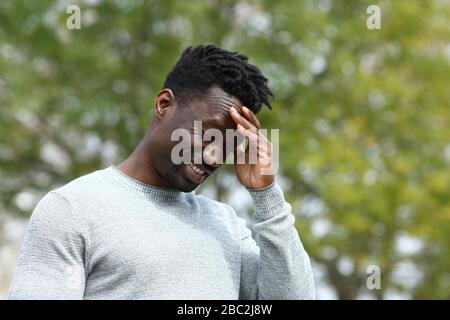 Black man suffering from painful head ache touching his temple with hand in a park Stock Photo