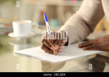 Close up of a black man hands filling out form on a desk at home Stock Photo