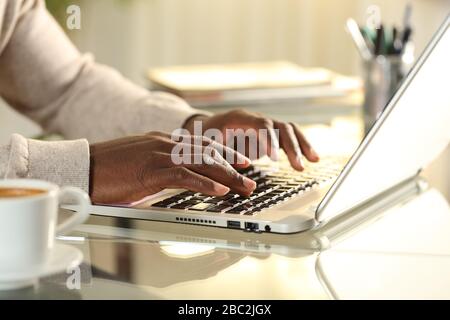 Close up of black man hands typing on a laptop on a desk at home Stock Photo