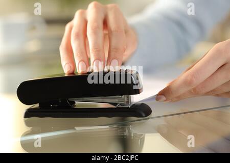 Close up of girl hands using stapler on documents over a desk at home Stock Photo