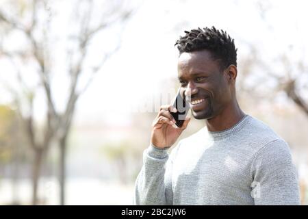 Happy black man talking on smart phone looking away in a park Stock Photo