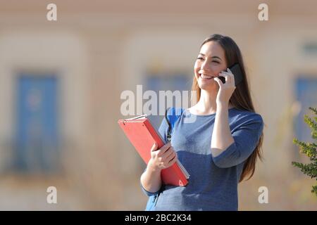 Happy student talks on mobile phone standing in an university campus Stock Photo