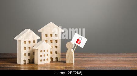 Residential buildings and man holding red padlock sign. Tough measures to stop new infections of coronavirus COVID-19 exponential growth. Self isolati Stock Photo