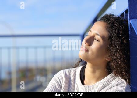Relaxed latina girl sitting on stairs leaning in a railing heating in a sunny day Stock Photo