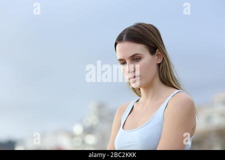 Sad woman complaining looking down in the street Stock Photo