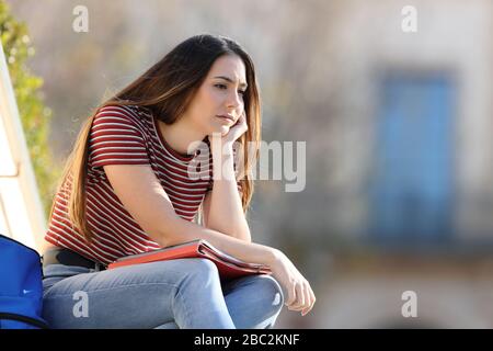 Sad student complaining looking away sitting in a campus Stock Photo