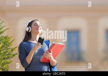 Student meditating listening to music holding smart phone in a campus a sunny day Stock Photo