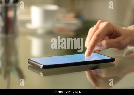 Close up of woman hands entering numbers on a lightened smart phone screen keyboard on a desk at home Stock Photo