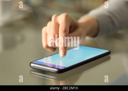 Close up of woman hand typing on a smart phone with lightened screen over a desk at home Stock Photo