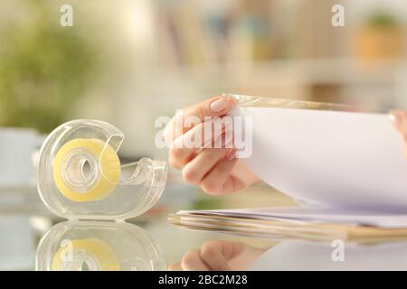 Close up of woman hands sticking adhesive tape on a paper on a desk at home Stock Photo