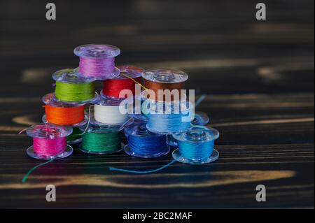 macro of colored cotton thread on yarn bobbins on brown wooden background in a stack Stock Photo