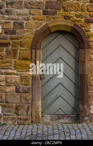 sandstone historic city wall with wooden door and door frame with sandstone round arch carved with special lock Stock Photo
