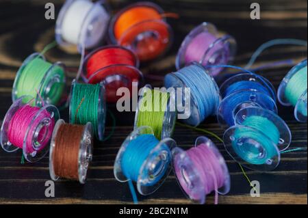 macro of multi colored cotton thread on yarn bobbins on wooden table Stock Photo