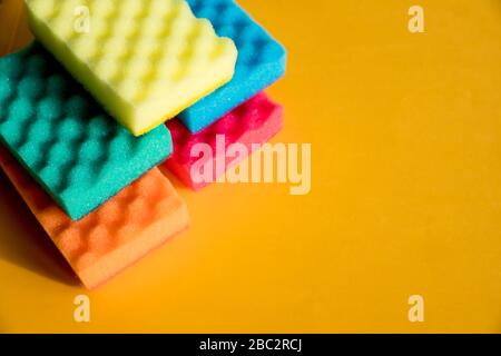 Multi-colored foam rubber sponge for cleaning and washing dishes on a orange background.Concept of cleaning of premises, offices and houses. This is a Stock Photo
