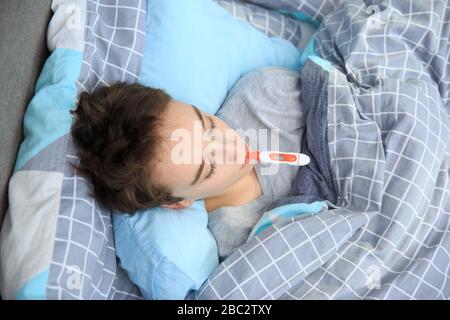 sick kid lying in bed with, Flue and fever , Sick child boy lying in bed with a fever, resting
