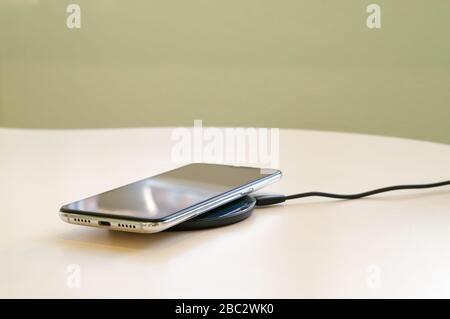 Smartphone wireless charging on induction charger. Wireless charger. Copy space. Stock Photo