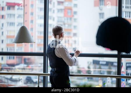 Smiling happy managing director thinks about his successful career development while standing with a cup of coffee in his hand in his office near the Stock Photo