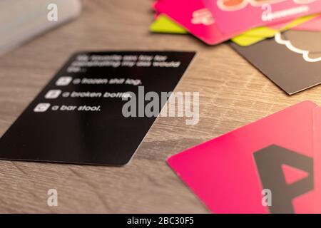 Black card representing a card board game. Answers blurred but barely visible. Multiple cards on the table, pink A in the corner. Stock Photo