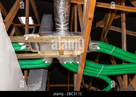 Home energy recovery ventilation, visible manifold and green flexible pipe connection, spread over the roof trusses. Stock Photo