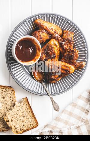 Grilled chicken wings on plate with BBQ sauce. Top view. Stock Photo